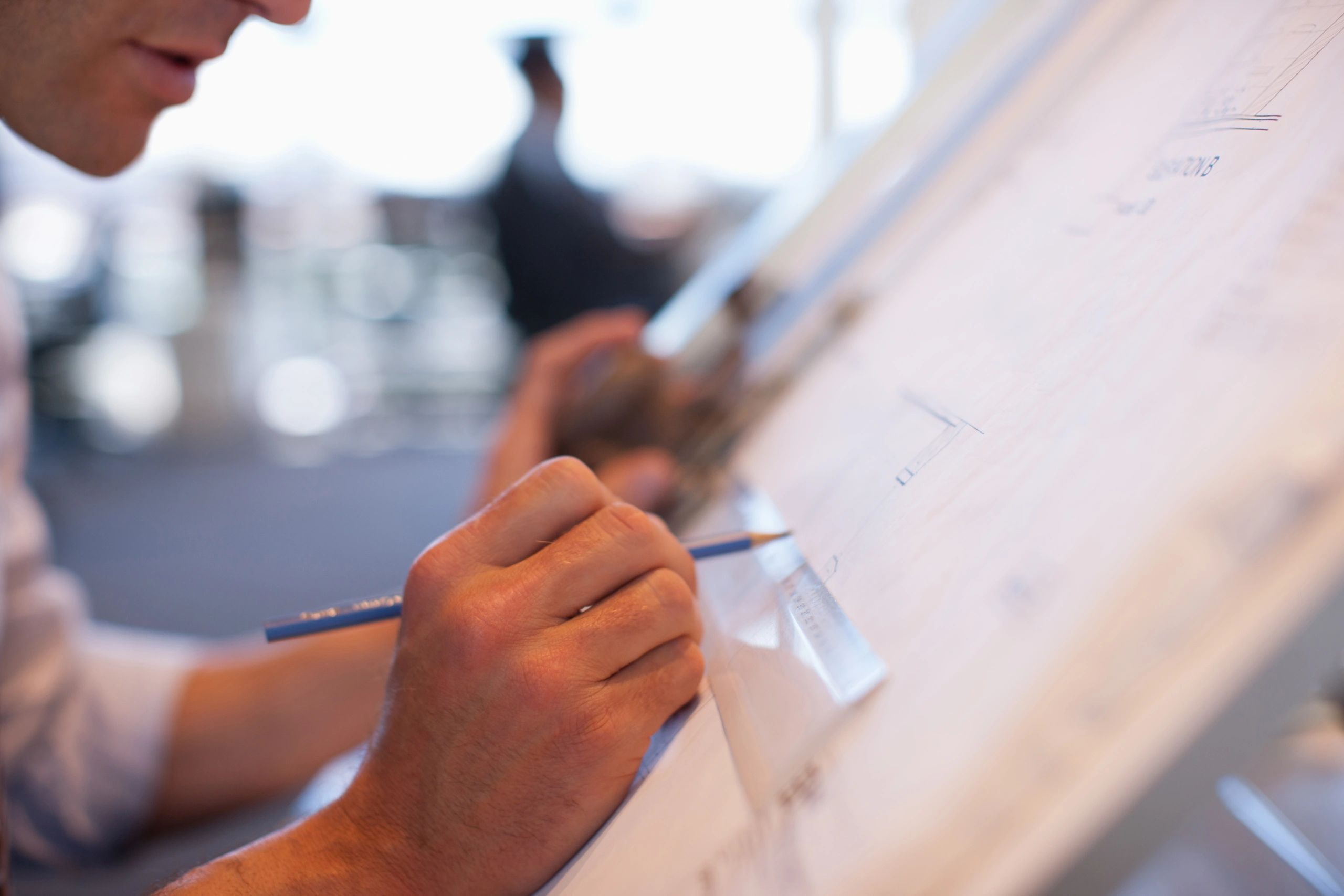 Professional reviewing drawings at a drafting table