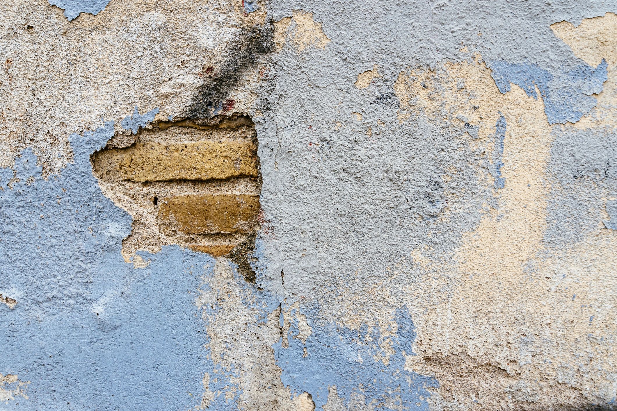Damaged exterior wall with peeling plaster showing need for repair